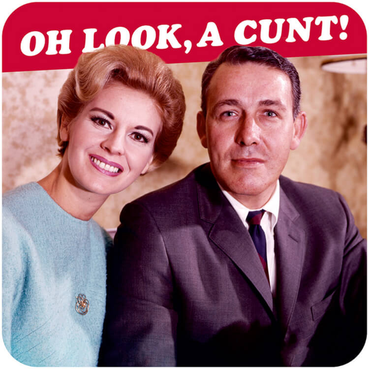 A coaster with a smiling male and female couple looking to camera sitting in front of a red banner with white text that reads Oh look, a cunt