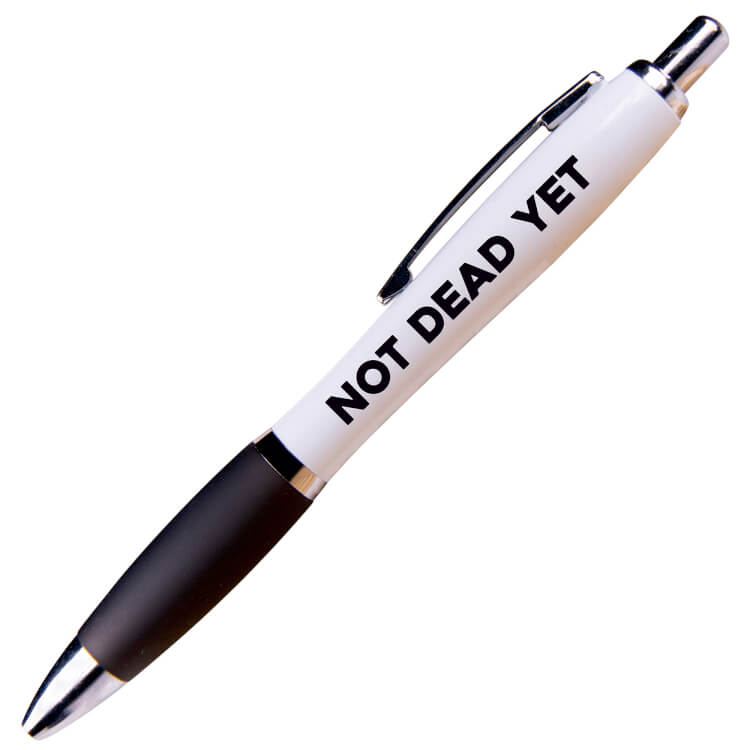 A white ballpoint pen with a black grip and black text that reads Not dead yet