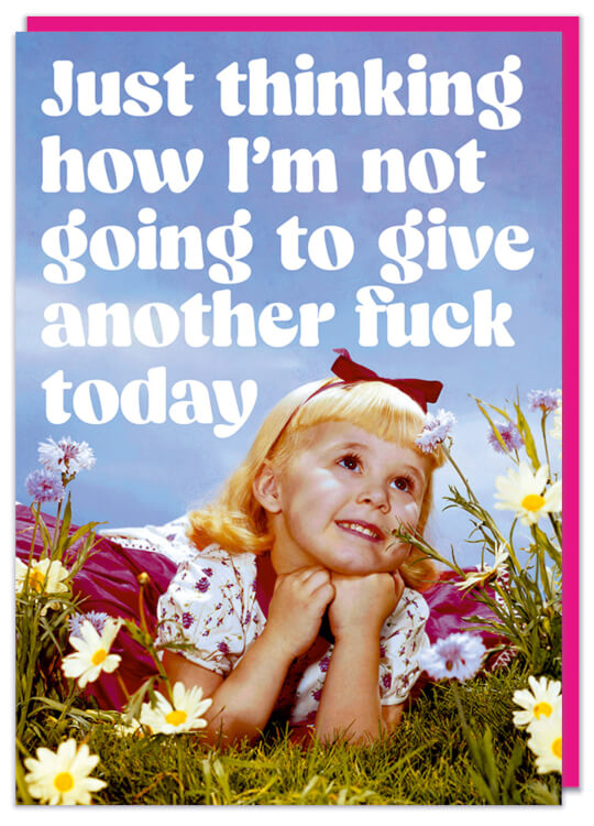 A greeting card with a retro picture of a sickly sweet girl lying down in a field of flowers looking up and smiling