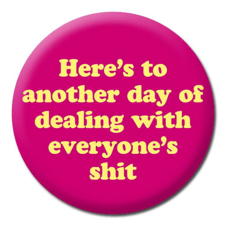 A dark pink badge with rounded yellow text that reads Here's to another day of dealing with everyone's shit