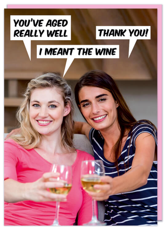 A birthday card with a modern photo of two young women drinking wine and holding to the camera.  One, in a pink dress says You've aged really well.  The other replies Thank you, to which she replies I meant the wine