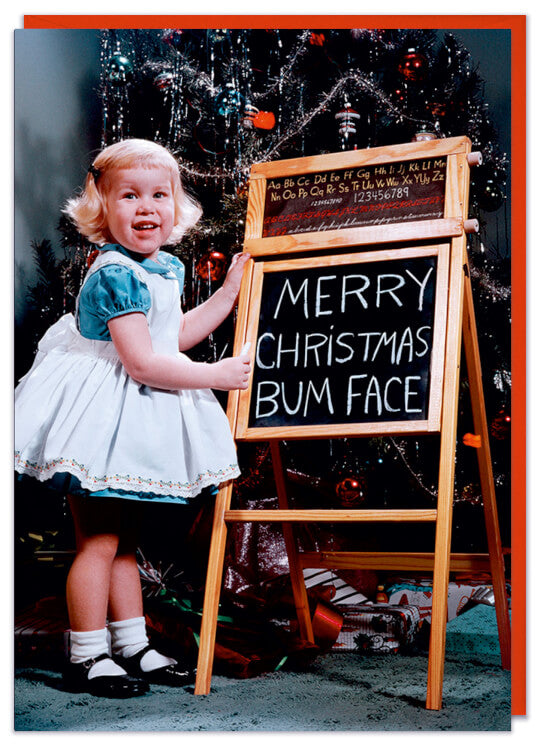 A Christmas card with a 1960s picture of a young girl standing a t a small blackboard on an easel