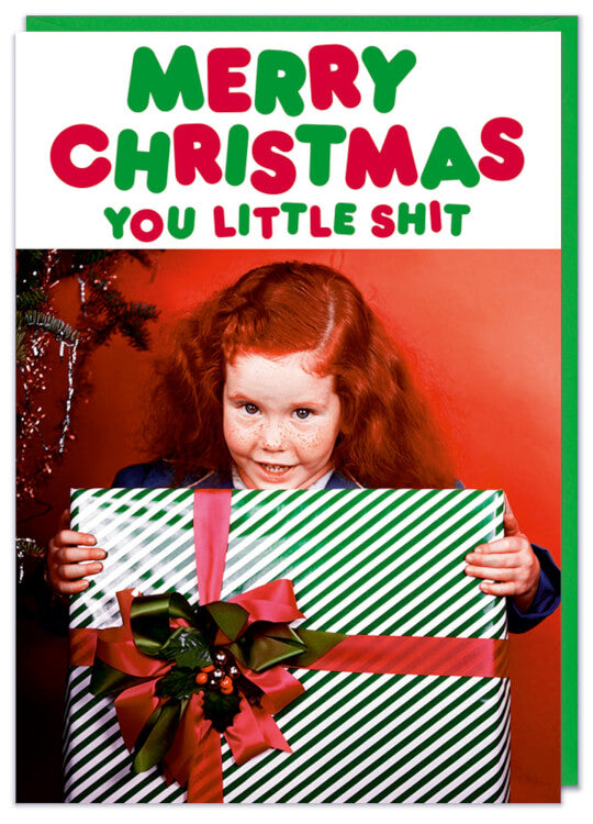 A Christmas card featuring a retro picture of a smiling precocious ginger haired child holding a large Christmas present