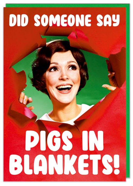A Christmas card featuring a 1960s picture of an excited woman bursting through a ripped wall of red paper.  White text above and below her reads Did someone say pigs in blankets?</