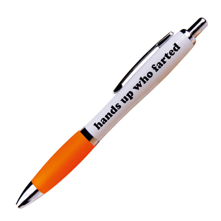 A white ballpoint pen with a orange grip and black ink. Black curvy text on one side reads Hands up who farted