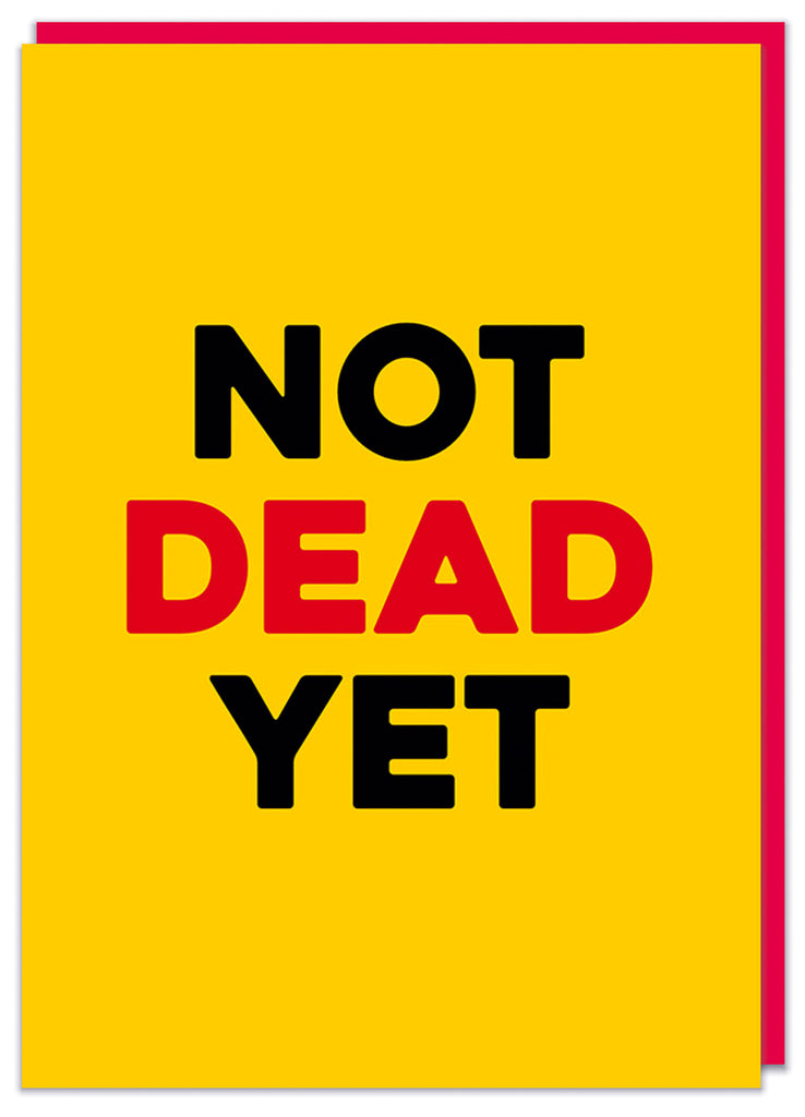 A dark yellow birthday card with bold capitalised black and red text that reads Not dead yet.